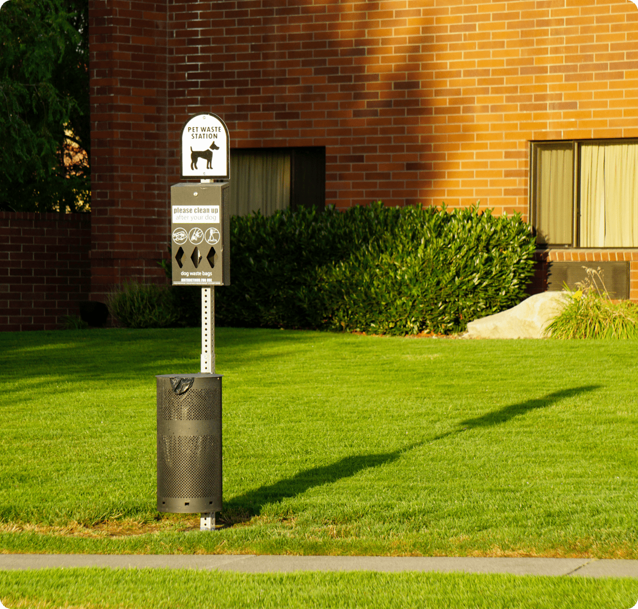 A parking meter in the grass near a building.