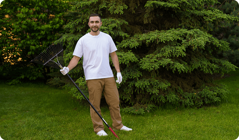 Man holding rake in a grassy yard.