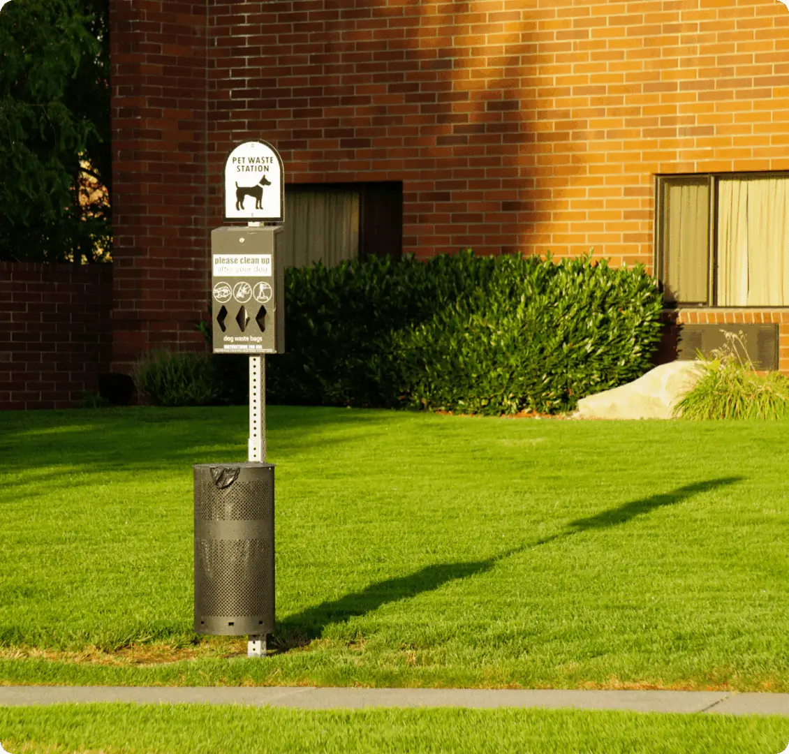 A parking meter in the grass near a building.
